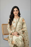 A woman seated on a woven-back chair wearing a cream-colored traditional outfit with floral prints and green border accents, photographed against a plain light gray studio background.